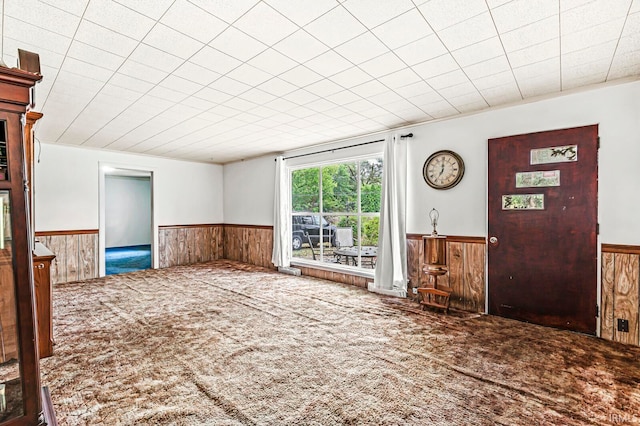 unfurnished living room featuring carpet floors and wooden walls