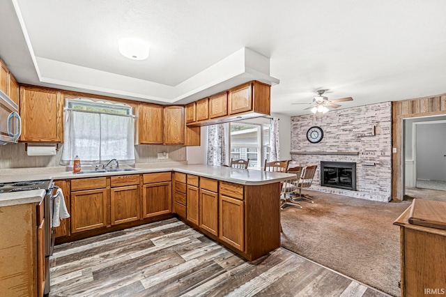 kitchen with a healthy amount of sunlight, kitchen peninsula, a fireplace, and light hardwood / wood-style flooring