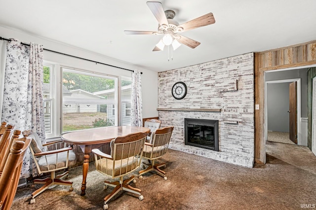 carpeted dining room with ceiling fan and a brick fireplace