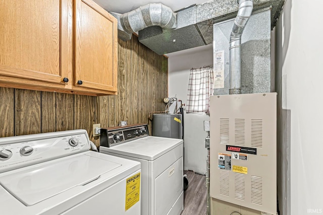 laundry room with washing machine and dryer, dark hardwood / wood-style flooring, gas water heater, and cabinets