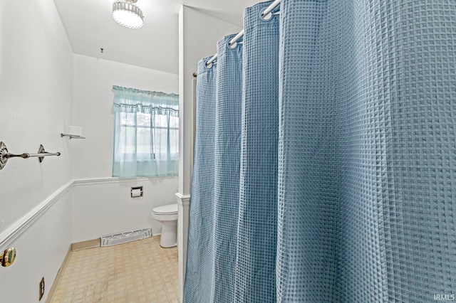 bathroom with a shower with curtain and toilet