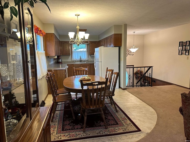 dining room with light colored carpet, a notable chandelier, sink, and a textured ceiling