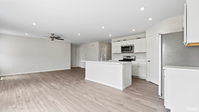 kitchen with ceiling fan, stainless steel appliances, light hardwood / wood-style flooring, an island with sink, and white cabinets