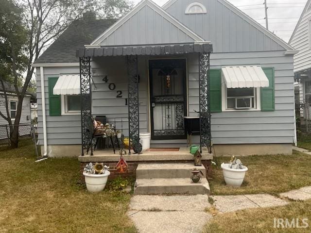 bungalow-style house featuring cooling unit, a front lawn, board and batten siding, and fence