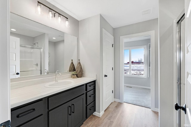 bathroom with hardwood / wood-style flooring, vanity, and a shower with door