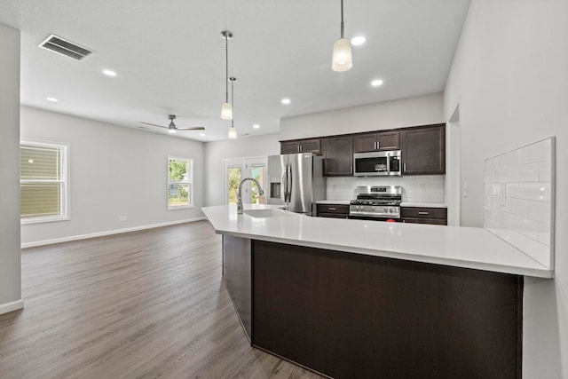 kitchen with ceiling fan, pendant lighting, dark brown cabinets, appliances with stainless steel finishes, and light hardwood / wood-style floors