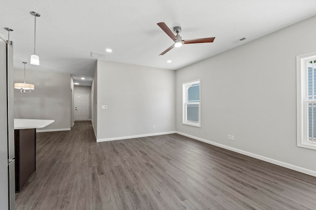 spare room with ceiling fan, dark wood-type flooring, and a wealth of natural light