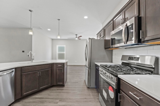 kitchen with hanging light fixtures, light hardwood / wood-style floors, stainless steel appliances, ceiling fan, and sink