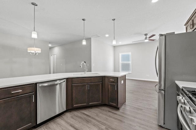 kitchen featuring appliances with stainless steel finishes, hanging light fixtures, light wood-type flooring, ceiling fan, and sink