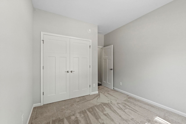 unfurnished bedroom featuring light colored carpet and a closet