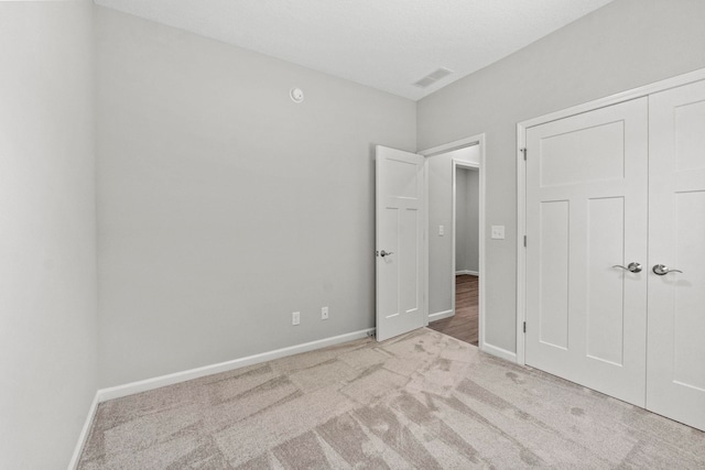 unfurnished bedroom featuring a closet and light colored carpet