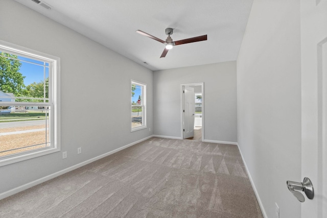 unfurnished room featuring light carpet, a wealth of natural light, and ceiling fan