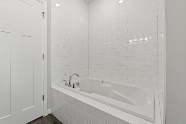 bathroom featuring tiled bath and hardwood / wood-style flooring