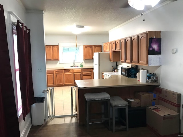 kitchen featuring ornamental molding, sink, kitchen peninsula, a textured ceiling, and light hardwood / wood-style flooring