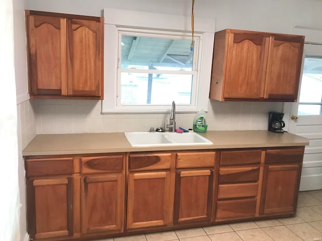 kitchen featuring a healthy amount of sunlight, light tile patterned flooring, sink, and tasteful backsplash