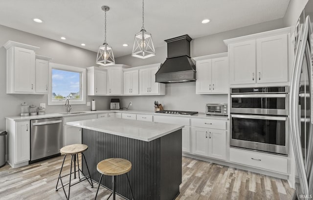 kitchen with white cabinets, custom range hood, appliances with stainless steel finishes, and a kitchen island