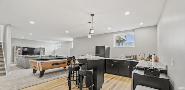 kitchen featuring light wood-type flooring, a kitchen bar, sink, and pendant lighting