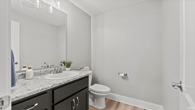 bathroom with vanity, hardwood / wood-style floors, toilet, and a textured ceiling