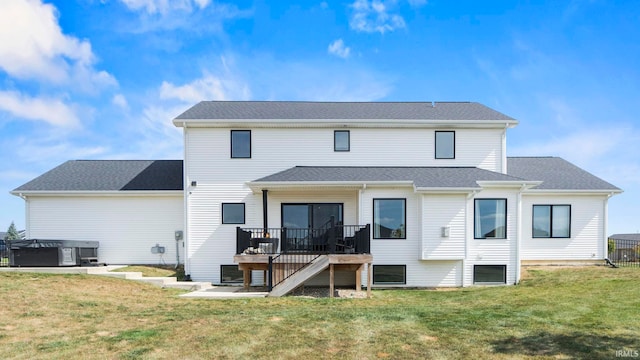 back of house featuring a deck, a yard, and a hot tub