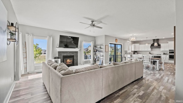 living room with ceiling fan, a textured ceiling, and hardwood / wood-style floors