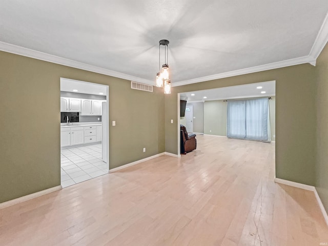 spare room featuring light hardwood / wood-style flooring, crown molding, and sink