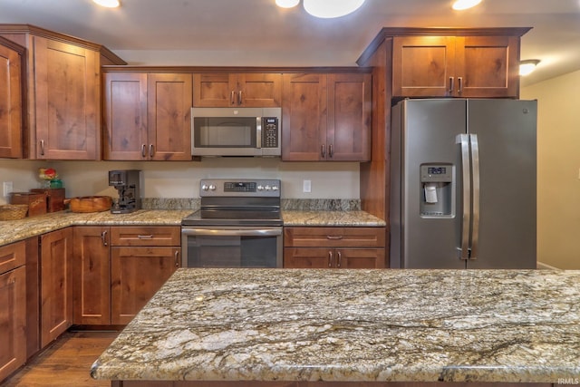 kitchen featuring dark hardwood / wood-style flooring, stainless steel appliances, and light stone counters