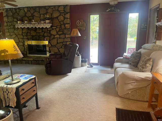 carpeted living room featuring ceiling fan, a fireplace, and plenty of natural light