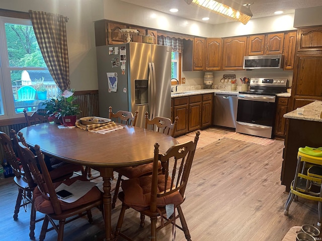 interior space with light wood-type flooring, sink, stainless steel appliances, and light stone counters