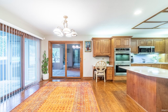 kitchen with a notable chandelier, stainless steel appliances, plenty of natural light, and light wood-type flooring