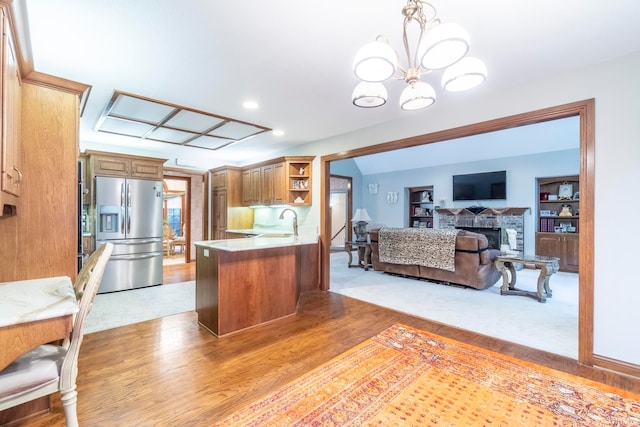 kitchen with sink, kitchen peninsula, decorative light fixtures, stainless steel fridge with ice dispenser, and an inviting chandelier