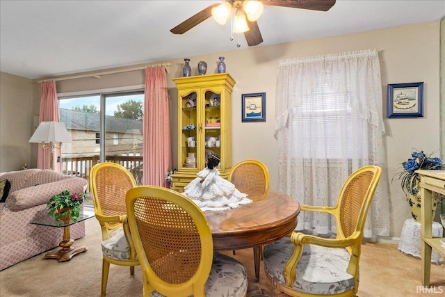 dining area with ceiling fan and light colored carpet