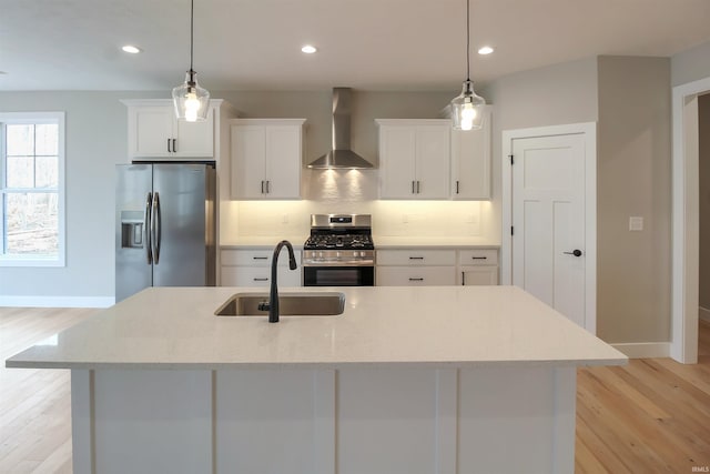 kitchen with hanging light fixtures, wall chimney exhaust hood, stainless steel appliances, and a sink