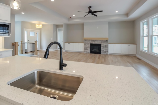 kitchen with light stone counters, a sink, and decorative light fixtures