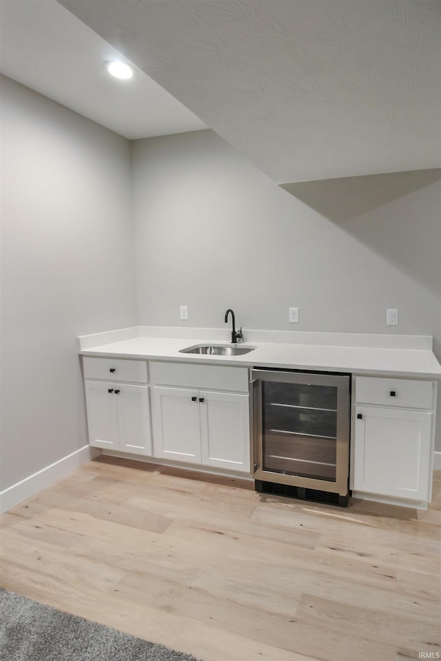 bar with beverage cooler, baseboards, light wood-style flooring, a sink, and recessed lighting