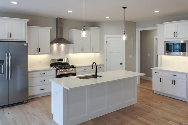 kitchen with wall chimney exhaust hood, appliances with stainless steel finishes, hanging light fixtures, light countertops, and a sink