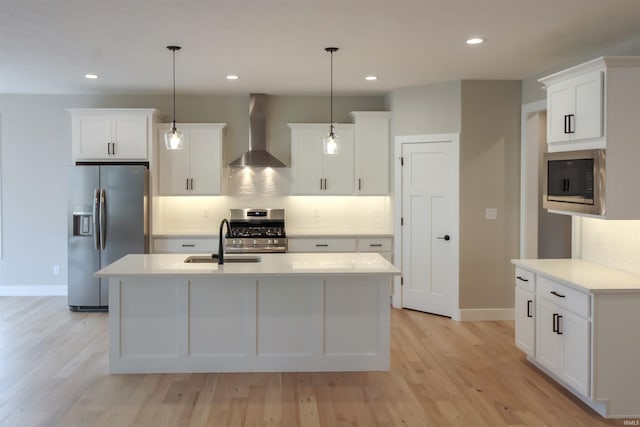 kitchen with wall chimney exhaust hood, appliances with stainless steel finishes, light countertops, and pendant lighting