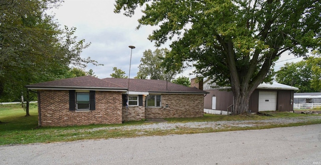 single story home featuring a front yard, a garage, and an outbuilding