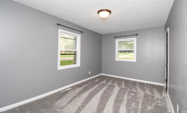 carpeted spare room with a textured ceiling