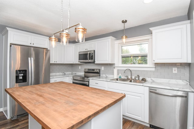 kitchen with white cabinetry, sink, pendant lighting, and stainless steel appliances