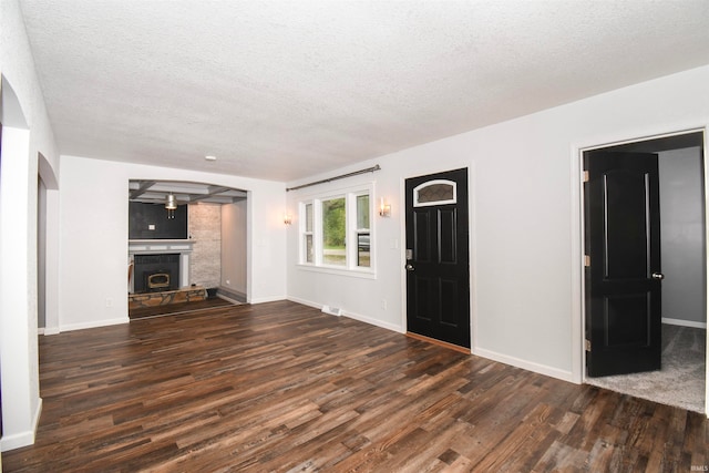 unfurnished living room featuring a textured ceiling, a tile fireplace, and dark wood-type flooring