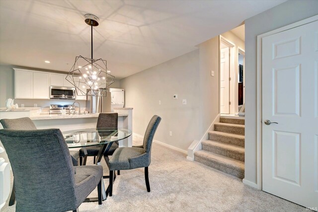 dining area with light carpet, sink, and a chandelier