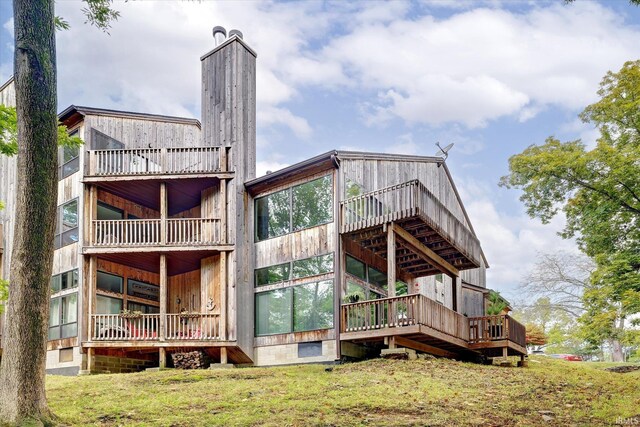 rear view of property featuring a balcony and a lawn