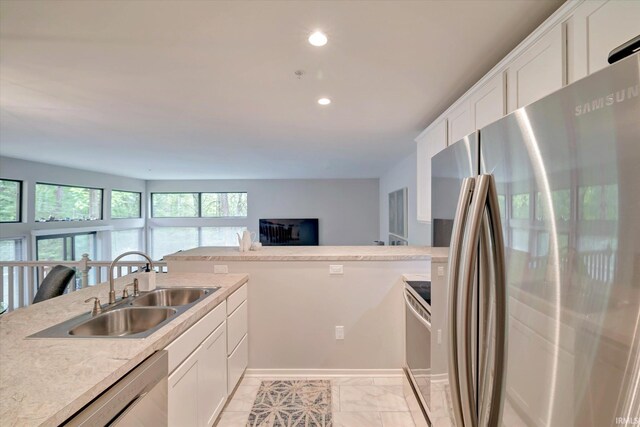 kitchen with appliances with stainless steel finishes, light stone countertops, white cabinetry, and sink