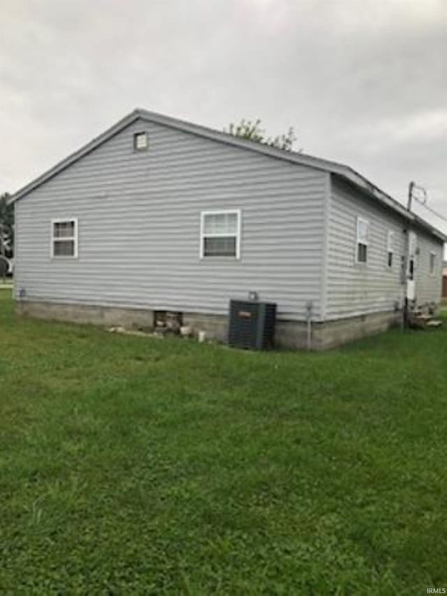 view of side of home featuring central AC unit and a lawn