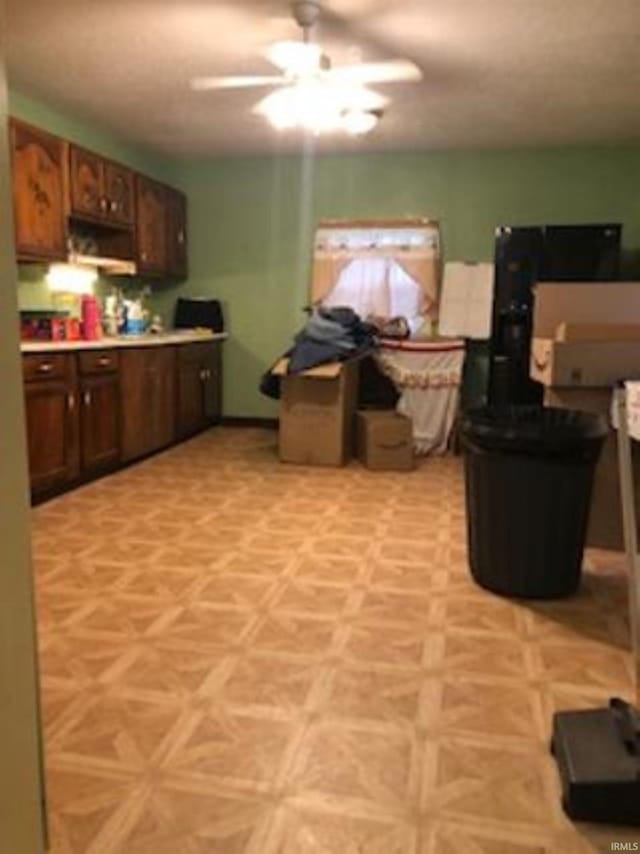 kitchen featuring ceiling fan, dark brown cabinetry, and light parquet flooring