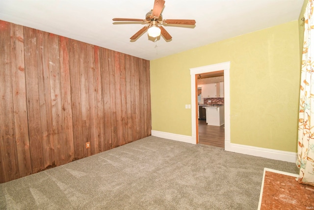 unfurnished room with wooden walls, ceiling fan, and carpet floors