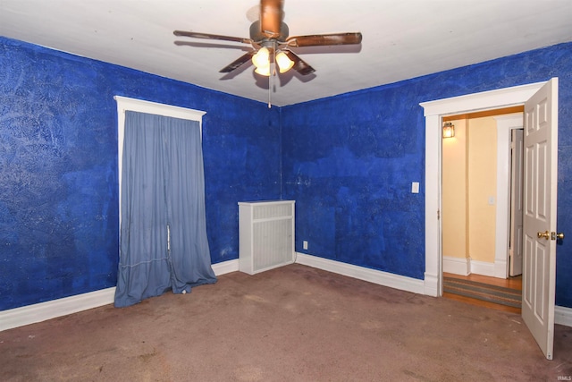 unfurnished room with ceiling fan and dark colored carpet