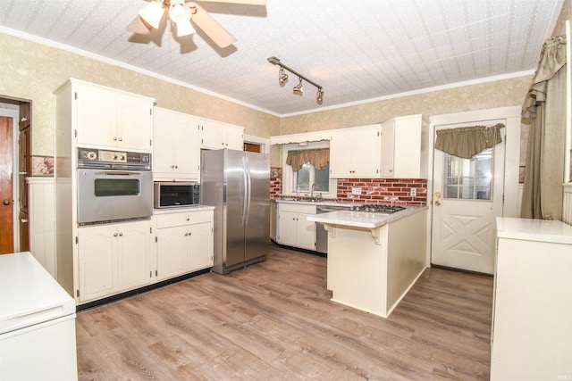 kitchen featuring ceiling fan, kitchen peninsula, white cabinetry, stainless steel appliances, and light hardwood / wood-style floors