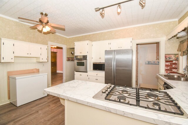 kitchen with hardwood / wood-style flooring, sink, stainless steel appliances, ornamental molding, and ceiling fan