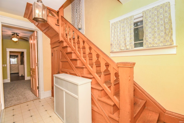 stairway featuring ceiling fan and carpet flooring